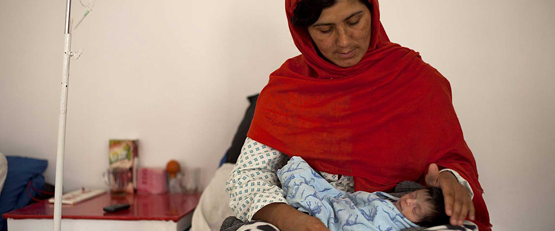 Una madre tiene in braccio il suo neonato nelle corsie del Centro di maternit&agrave; di Anabah, in Afghanistan