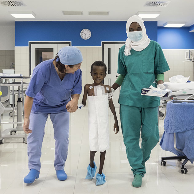 A child walks with a doctor and a nurse in a ward at the Salam Centre for Cardiac Surgery in Khartoum, Sudan